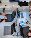 Fire mennesker sidder med hver deres computer om et bord