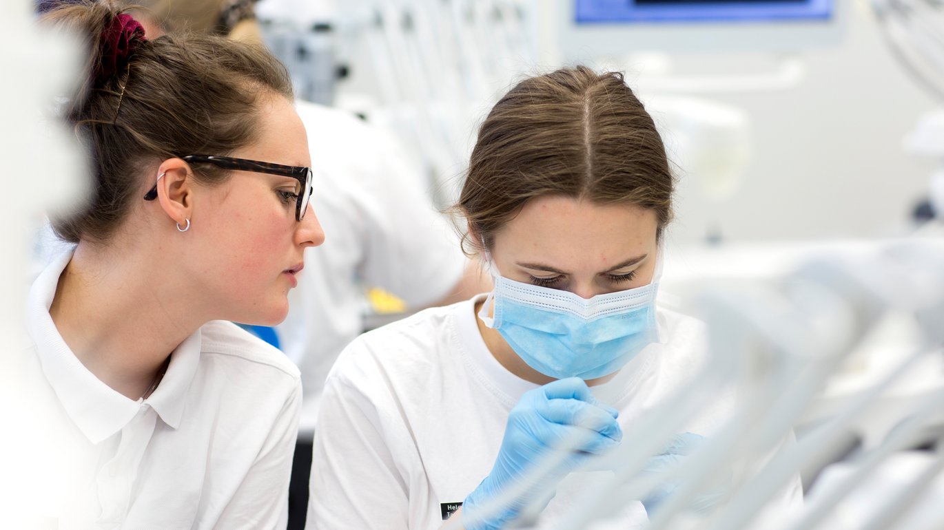 Billedet viser to kvindelige studerende ved en dental unit i universitetsklinikken