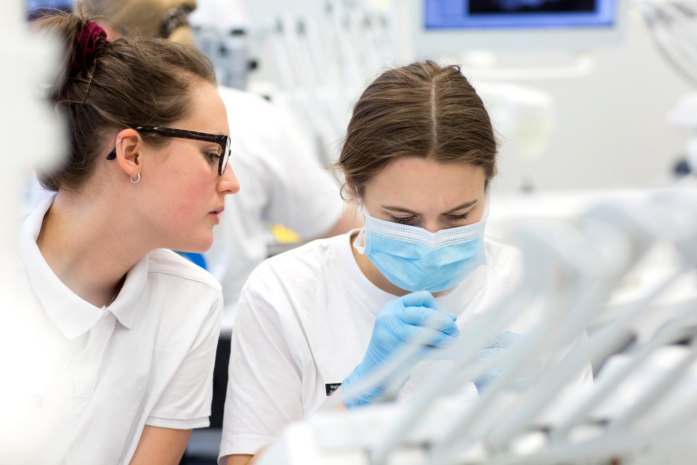 Photo shows two female students at a dental unit in the university clinic