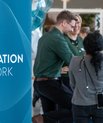 På billedet ses et skilt med teksten The Inflammation Network og i baggrund står tre glade deltagere 